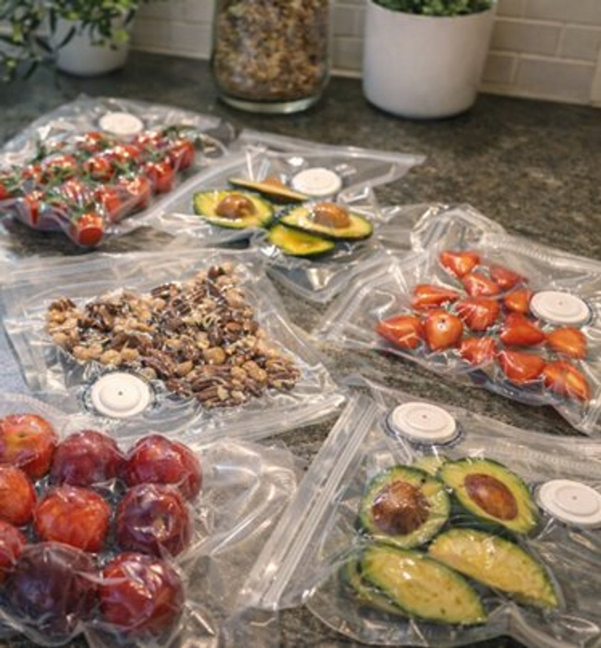 Køkkenbord dækket af vakuumerede poser med tomater, bær og avocado